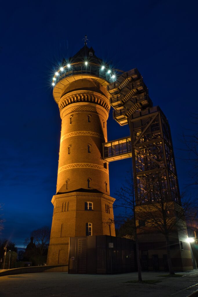 Ein ehemaliger Wasserturm in Mühlheim an der Ruhr, in dem das Aquarius Wassermuseum beheimatet ist. Der Wasserturm ist mit Natriumdampflampen beleuchtet.